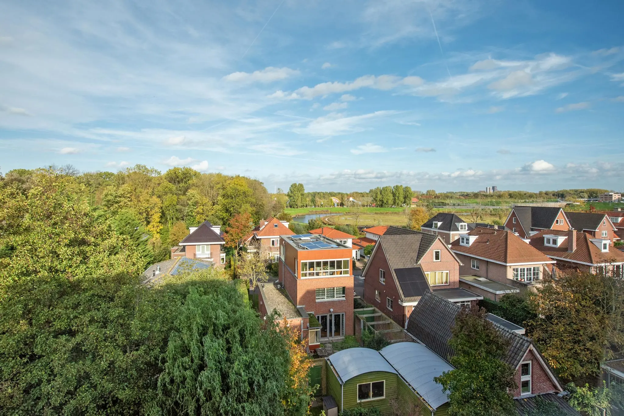 Luchtfoto van een woonwijk aan de Laan van Vredenoord met huizen, bomen en weids landschap op de achtergrond.